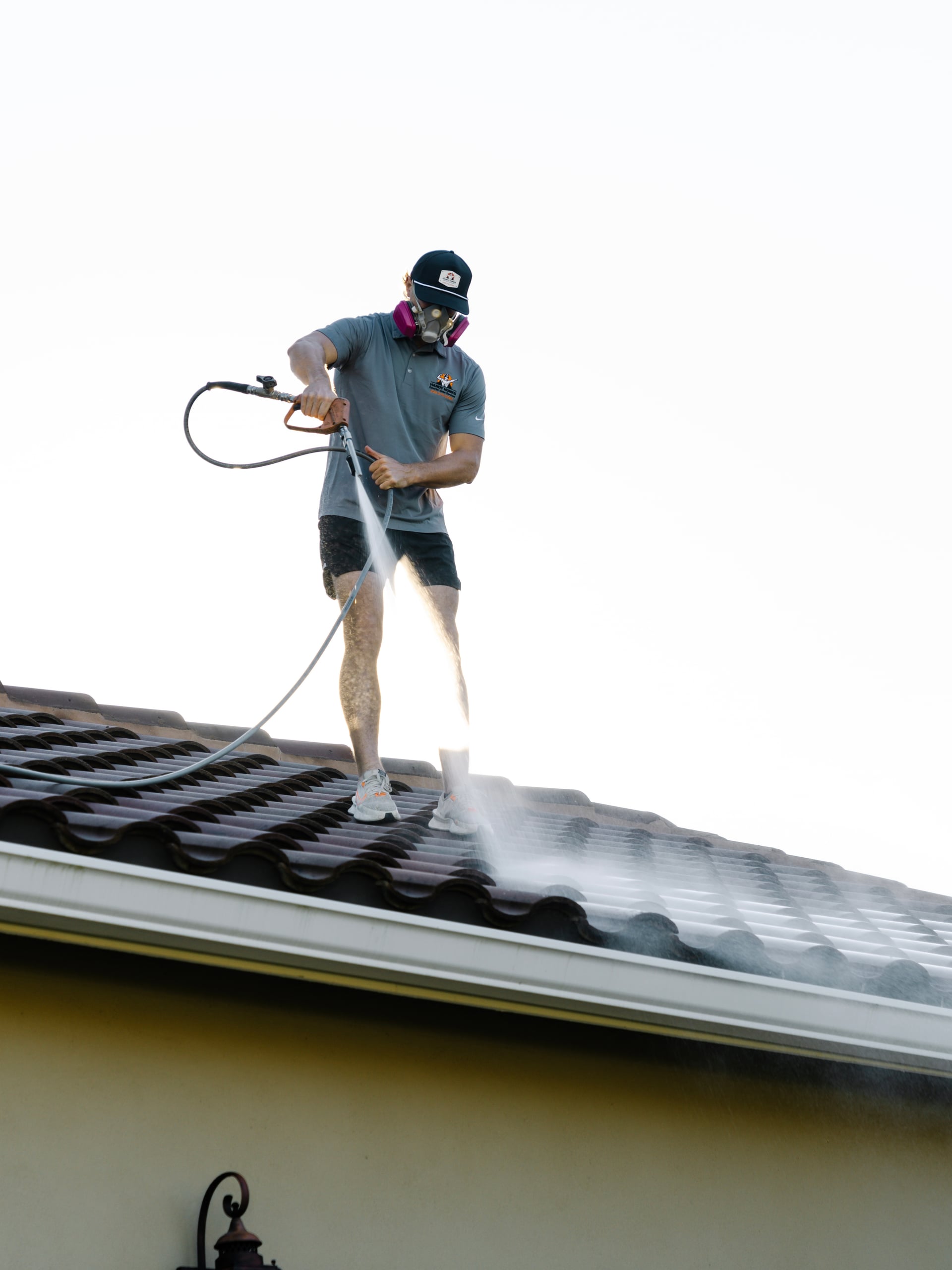 Technician soft washing a tile roof